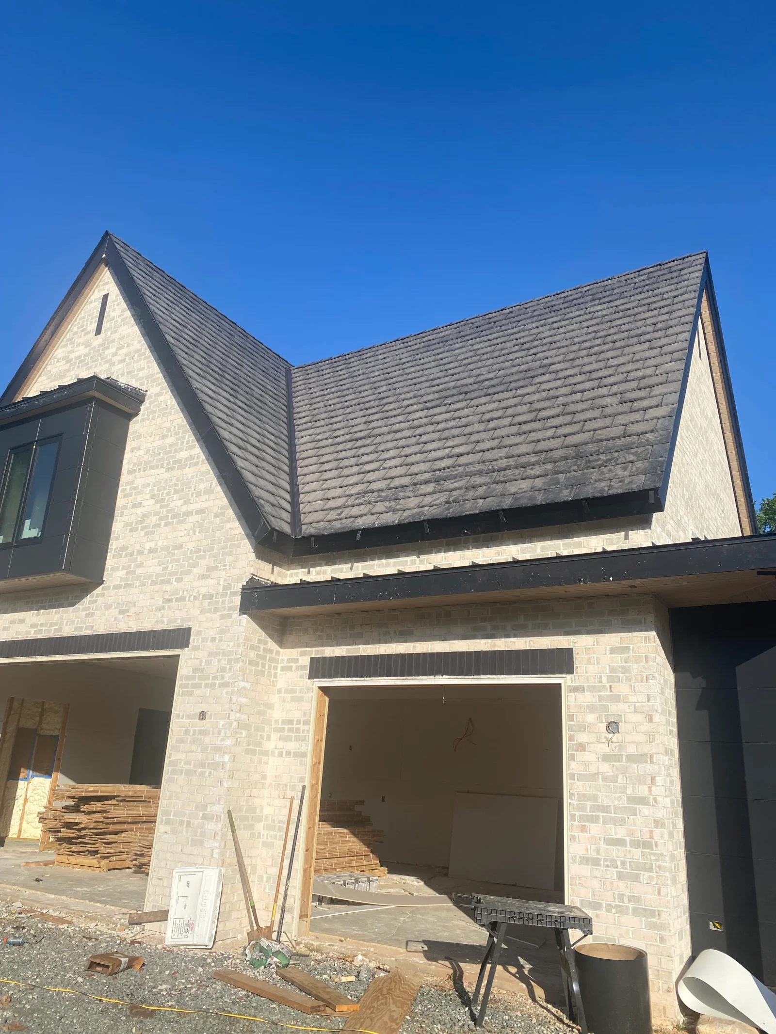 Charcoal gray architectural shingles installed on two-story brick home with gable roof design