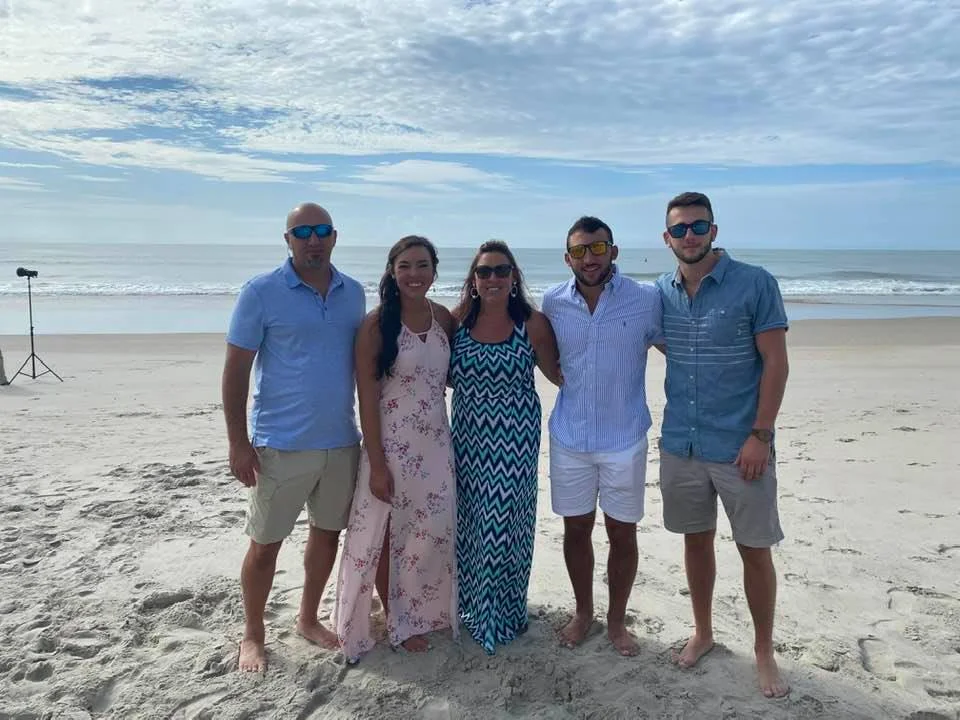 Five people standing on beach sand with professional photography lighting equipment and tripod setup